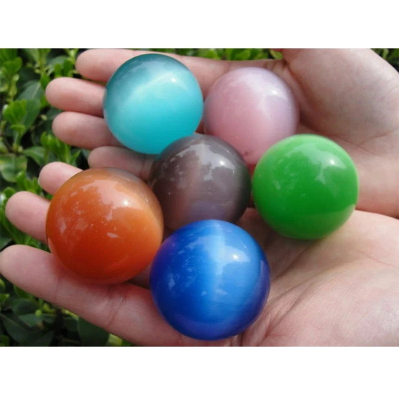 Hand holding five colorful marbles against a natural background