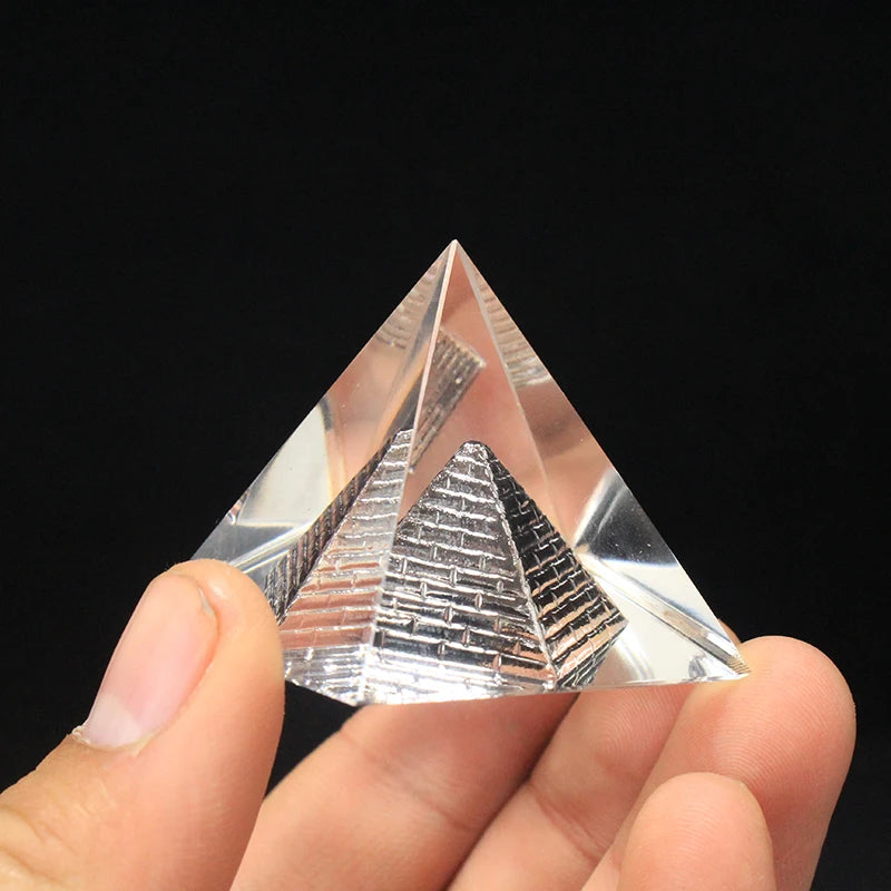 Clear crystal pyramid held between fingers against a black background