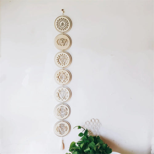 Decorative wall hanging with chakra symbols on a white wall.