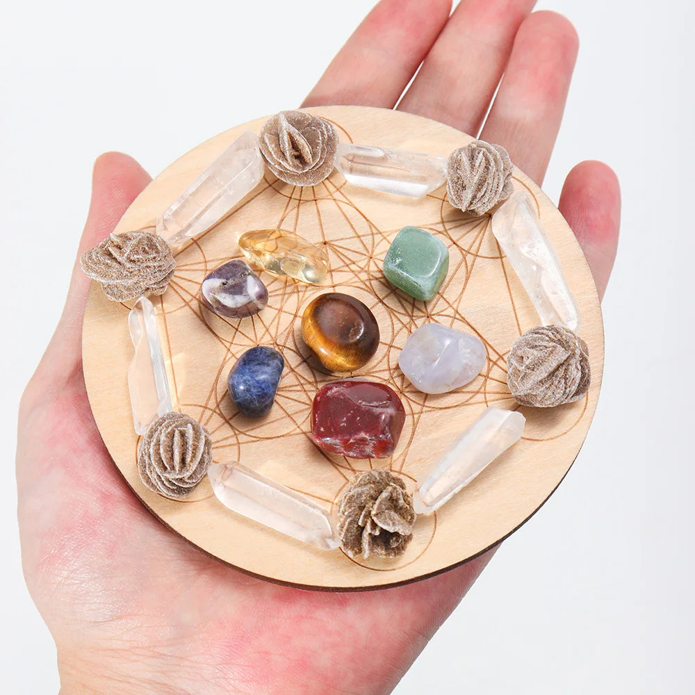 Hand holding a wooden crystal grid with various crystals on a white background