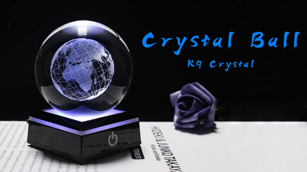 Crystal ball with Earth design on a stand, next to a purple rose, on a dark background.