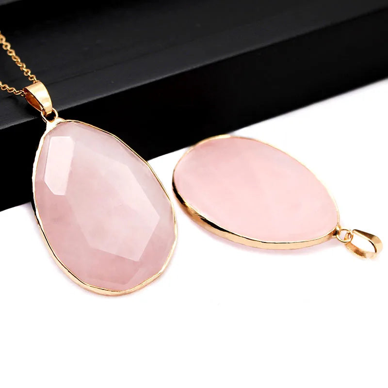 Two pink teardrop pendants with gold frames on a white background
