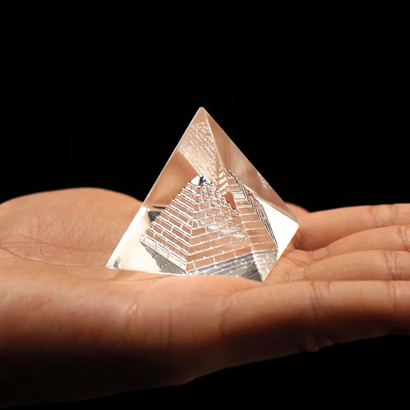 Clear pyramid crystal held in a hand with a dark background