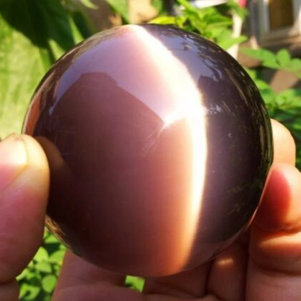 Person holding a shiny, reflective brown sphere with a blurred green background
