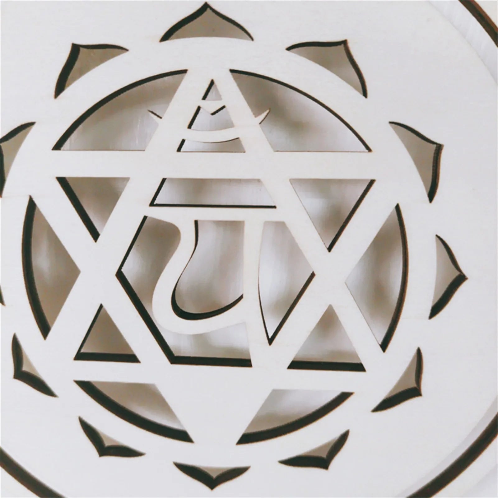 Decorative white object with geometric cut-out design on a light background