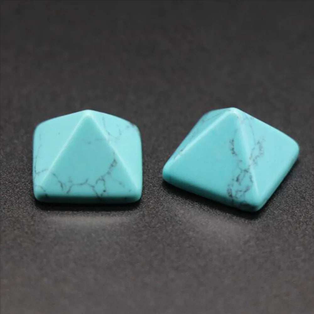 Two turquoise pyramidal stones on a dark gray background