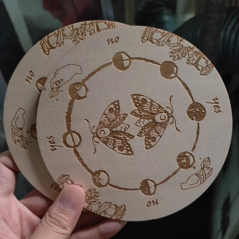 Wooden circular object with engraved designs and butterfly illustrations, held by a hand.