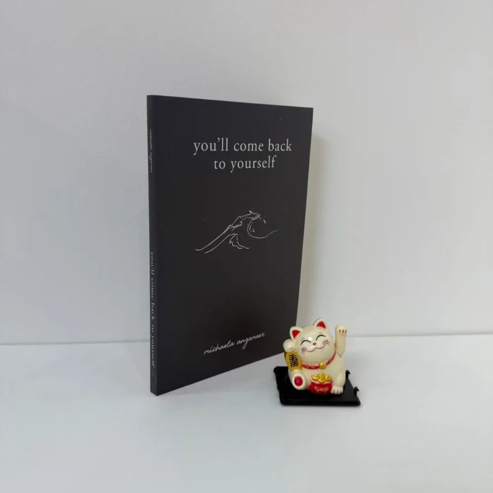 Black book with text and a small figurine on a white background