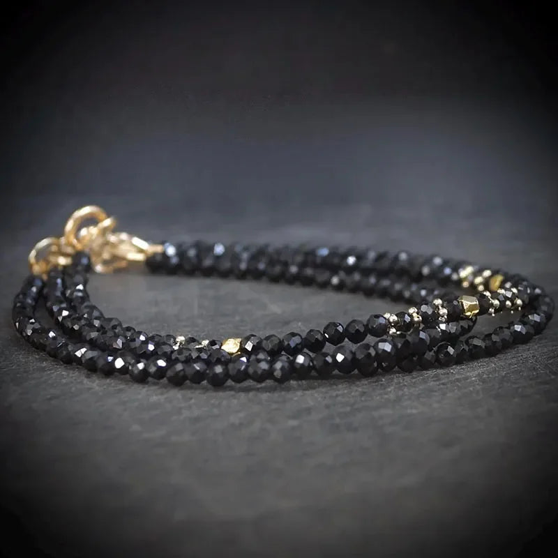 Black beaded necklace with gold clasp on a dark surface