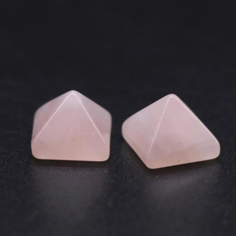 Two pink pyramid-shaped stones on a dark surface