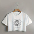 White crop top with sun and moon design and text on a hanger against a gray background