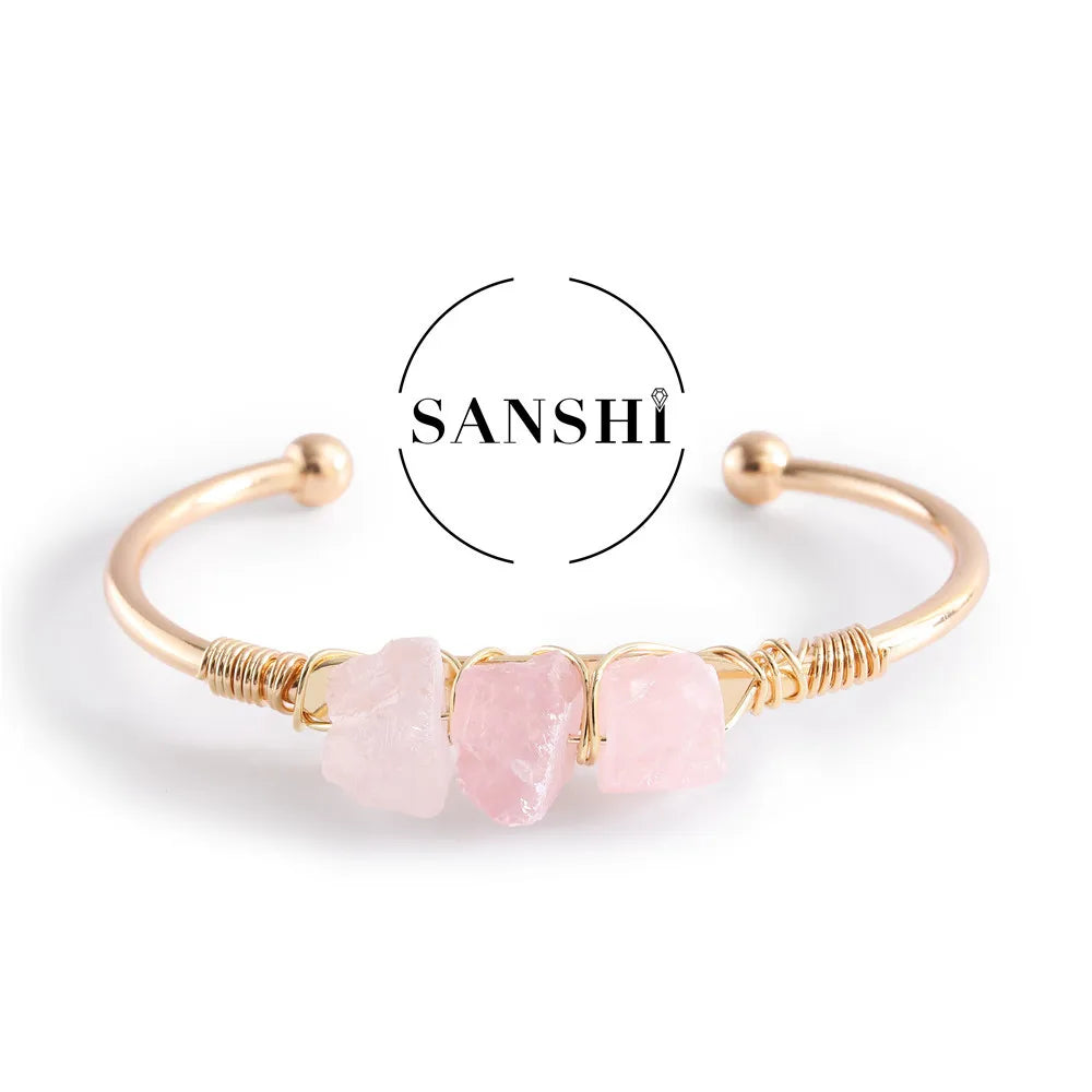 Gold bracelet with pink stones on a white background, featuring the brand 'Sanshi'.