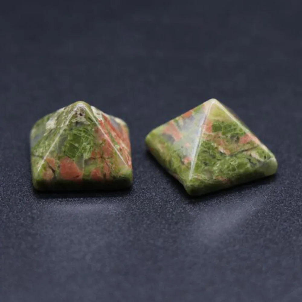Two green pyramidal stones on a dark surface