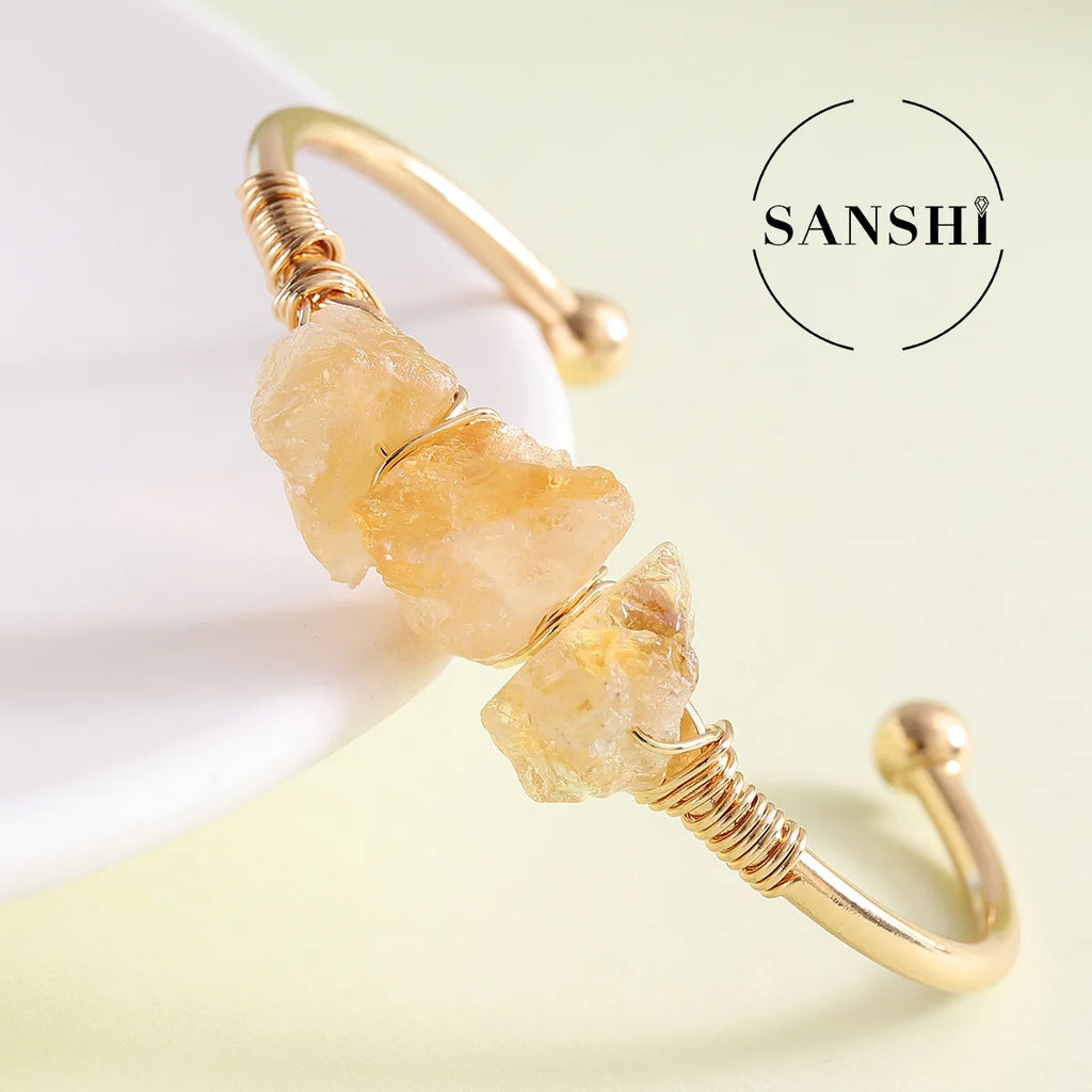 Gold bracelet with natural stones on a light background, featuring the brand 'Sanshi'.