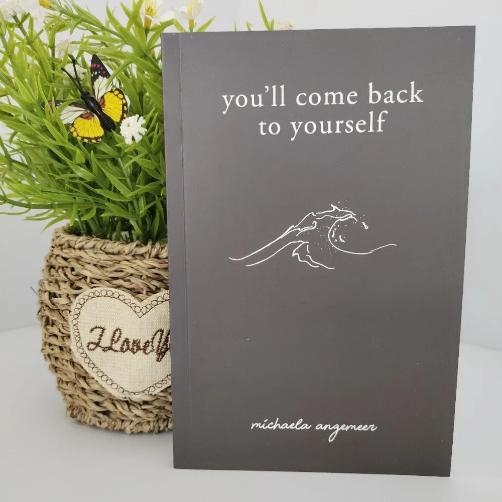 Book titled 'you'll come back to yourself' by Michaela Angemeir with a plant and butterfly decoration.