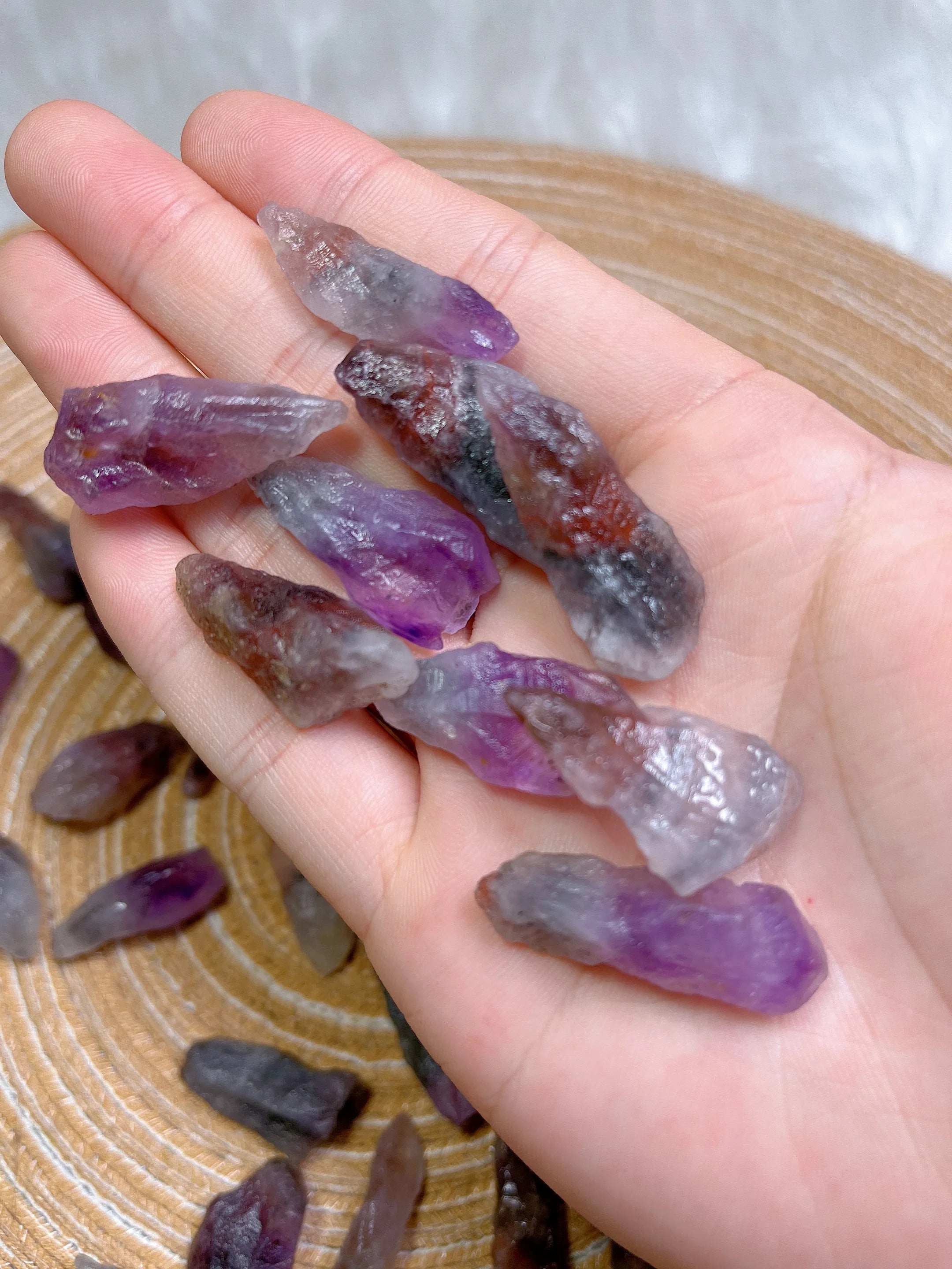 Hand holding purple crystal rocks with a wooden surface in the background