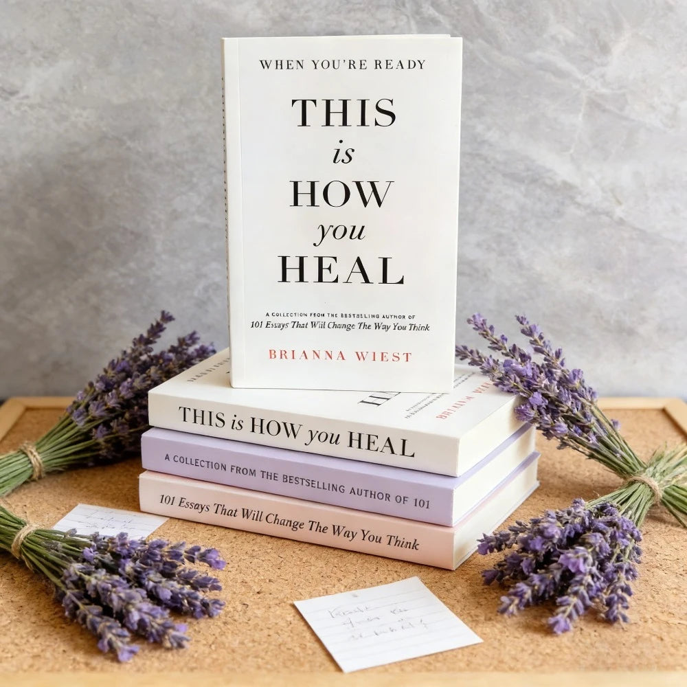 Stack of books titled 'This is How You Heal' with lavender on a wooden surface.