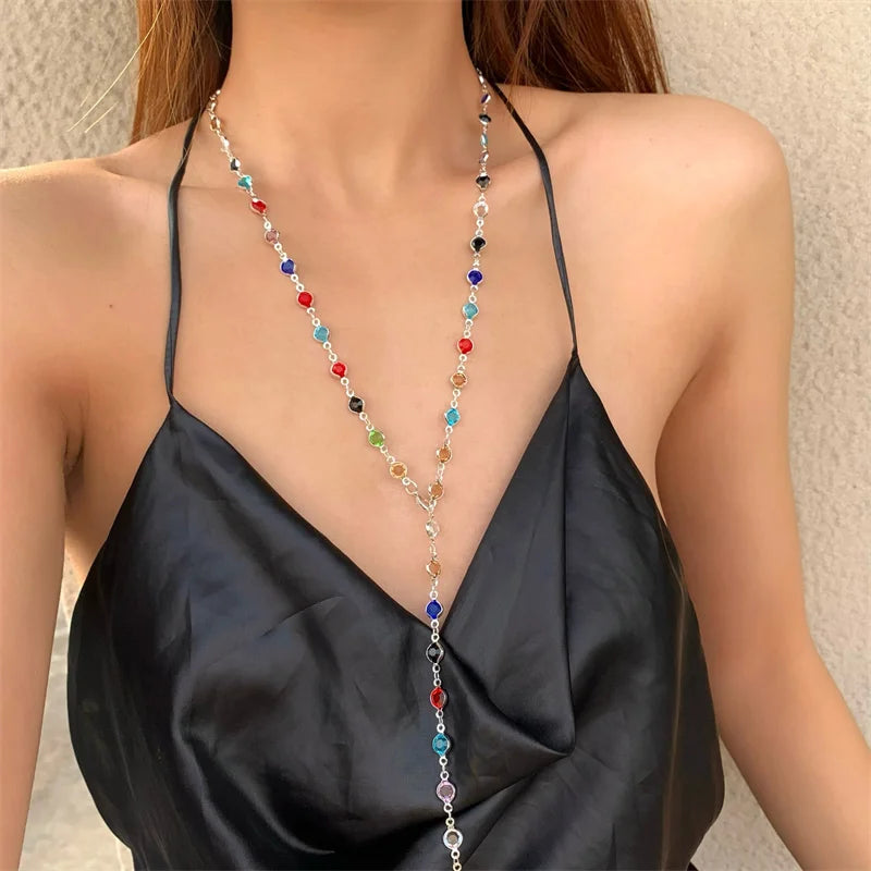 Woman wearing a black strappy top with a colorful beaded necklace against a neutral background
