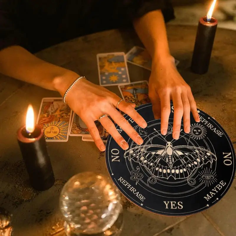 Person with hands on a tarot card surrounded by candles and tarot cards on a wooden table.