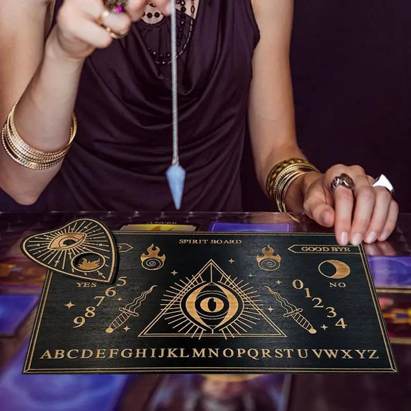 Person with tarot cards and a spirit board on a table, with a dark background.