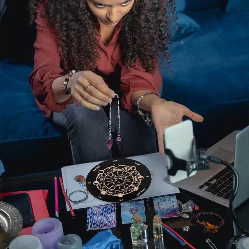 Woman examining a necklace with an astrological symbol on a table with tarot cards and other items.