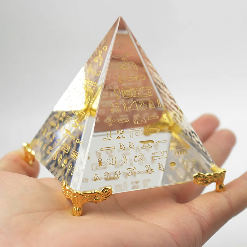 Crystal pyramid with hieroglyphics held in a hand against a white background