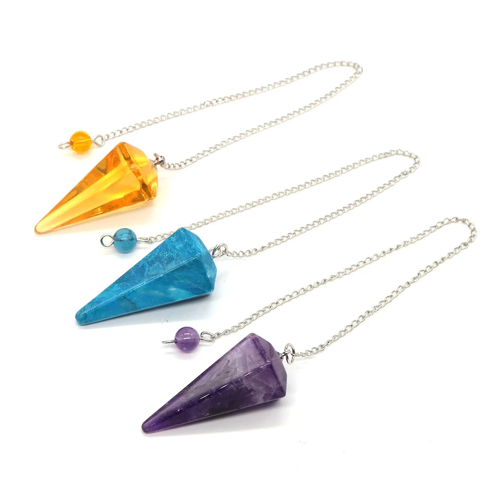 Three crystal pendulums on silver chains against a white background