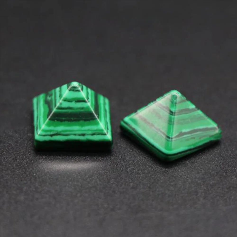 Two green pyramid-shaped objects on a dark surface