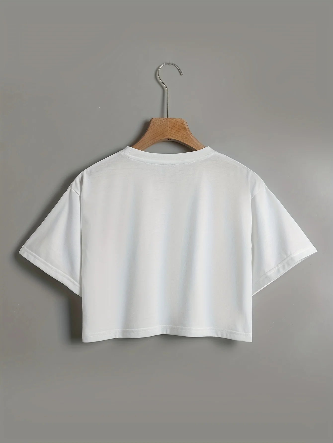 White t-shirt on a wooden hanger against a gray background