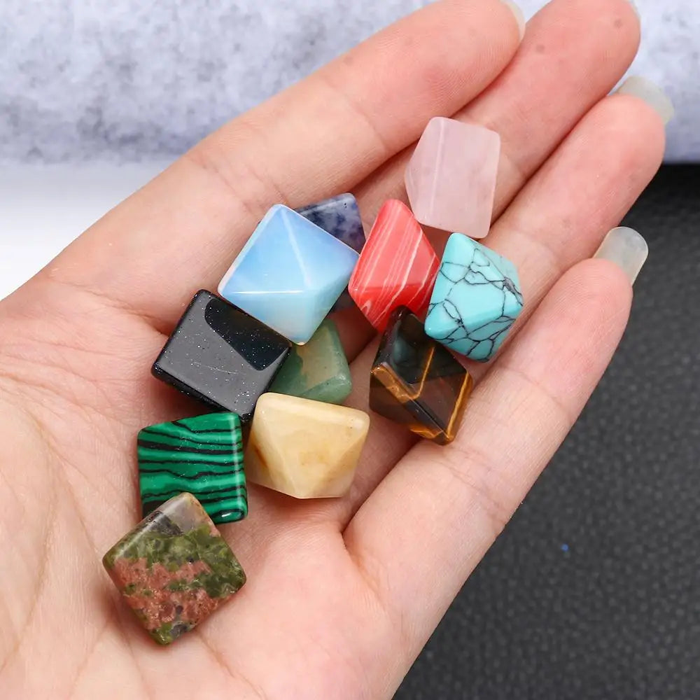 Hand holding a collection of multicolored gemstones on a neutral background