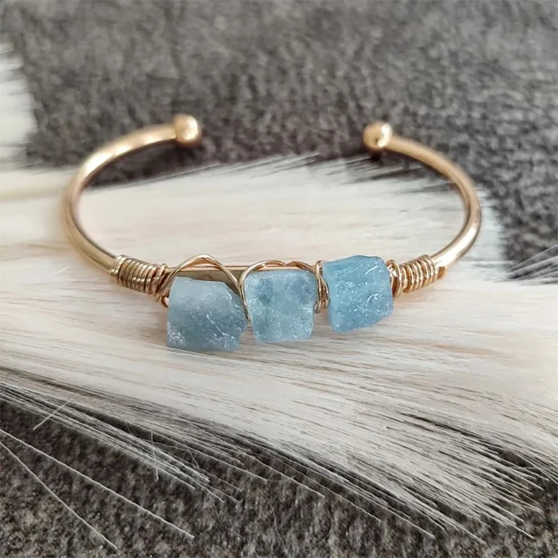 Gold bracelet with blue stones on a textured surface