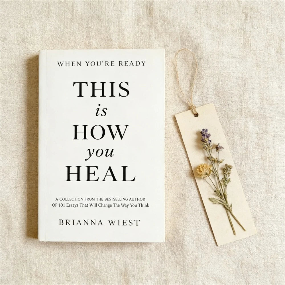 Book titled 'This is How You Heal' by Brianna Wiest with a bookmark featuring dried flowers on a textured surface.